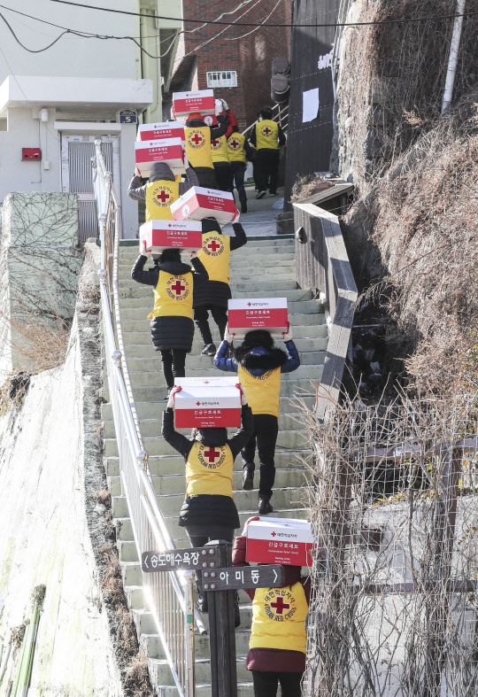 지난 8일 부산 서구 남부민동에서 적십자사 부산지사 봉사자들이 저소득 가정에 전달할 구호품을 이고 지고 이동하고 있다. 연합뉴스
